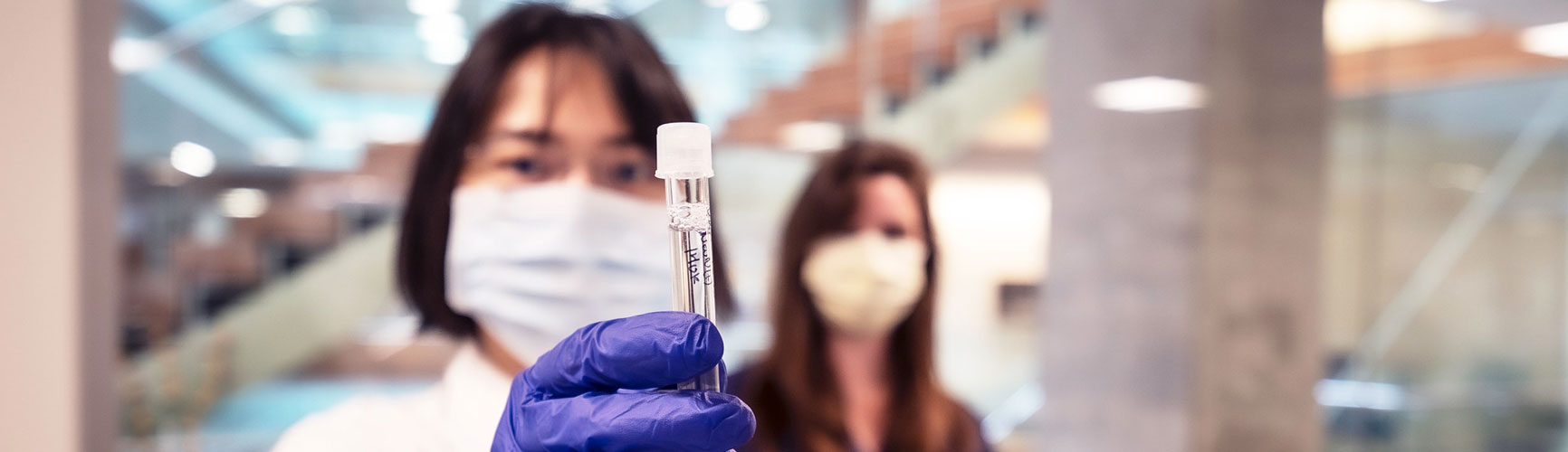 A researcher wearing protective equipment holds a vial while working in a lab at the Allen Institute